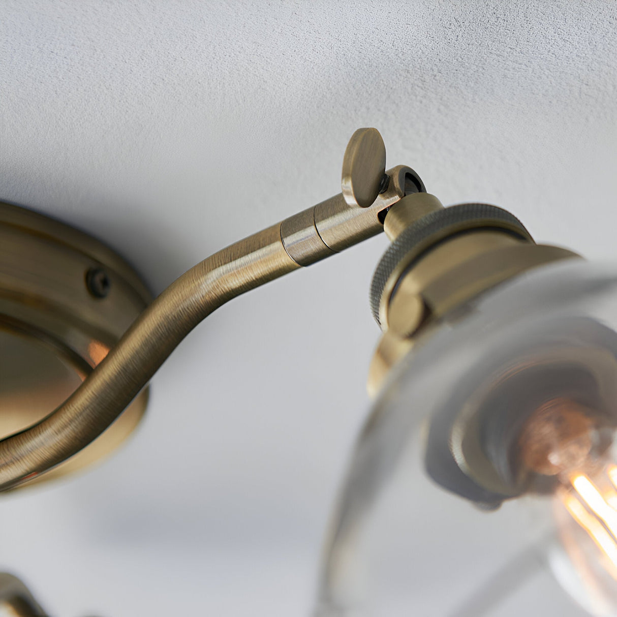 Close-up of the Wentworth 3 Light Semi-Flush Ceiling Light in antique brass with an adjustable knurled arm joint and glass shade.