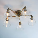 Endon Wentworth 5 light semi-flush ceiling light in antique brass with curved arms and clear glass bell shades, mounted on a pale ceiling.