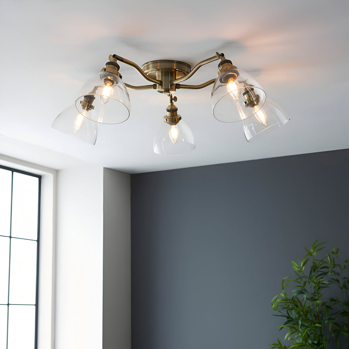 Endon Wentworth 5 light semi-flush ceiling light in antique brass with clear glass bell shades, installed on a white ceiling in a bright corner room.