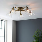 Endon Wentworth 5 light semi-flush ceiling light in antique brass with clear glass bell shades, installed on a white ceiling in a bright corner room.