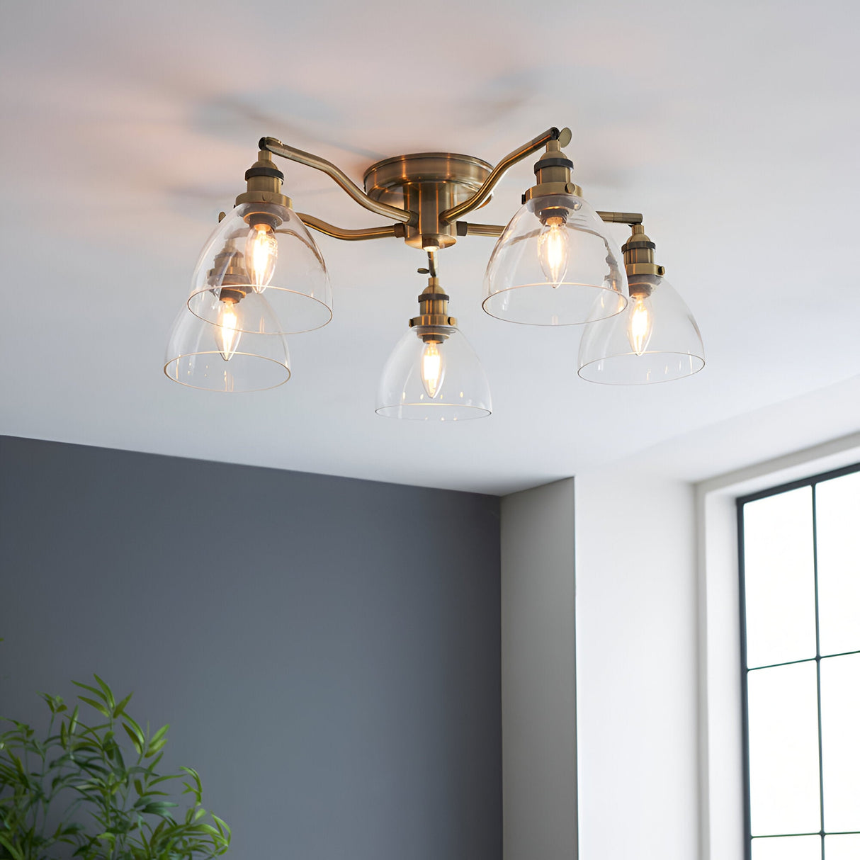 Endon Wentworth 5 light semi-flush ceiling light in antique brass with clear glass dome shades, installed on a white ceiling in a bright room.