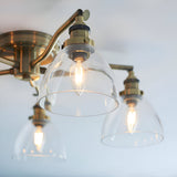 Close-up of Endon Wentworth semi-flush ceiling light in antique brass, showing curved arms holding clear glass dome shades with lit E14 filament lamps.