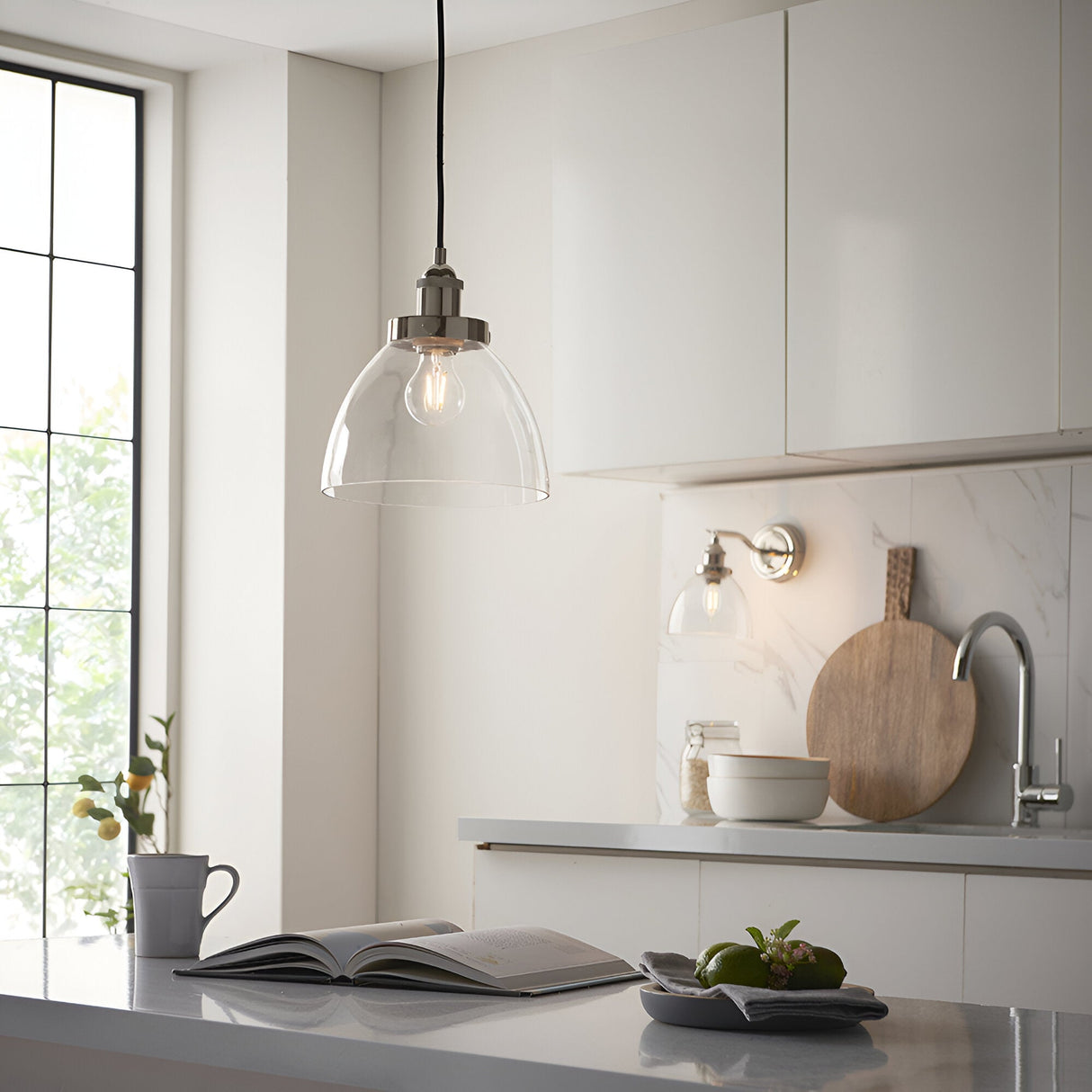Endon Wentworth nickel wall light with clear glass dome shade mounted on a marble splashback in a white kitchen, with a matching pendant above.