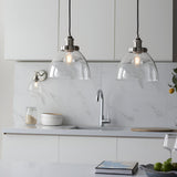 Endon Wentworth nickel wall light with clear glass shade beside two matching pendant lights over a white marble kitchen sink area.