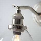 Close-up of Endon Wentworth wall light in nickel, showing knurled E14 lamp holder, adjustable knuckle, toggle switch and clear glass shade with filament bulb.