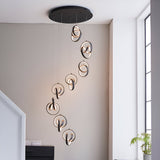 Endon Bevwell 8 light pendant in matt black, with swirling looped LED rings cascading in a spiral drop in a bright modern stairwell.