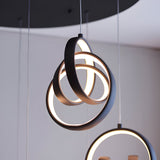 Endon Bevwell 8 light pendant in matt black, with looped metal rings clustered into a sculptural form glowing warm white, shown alongside a second pendant.