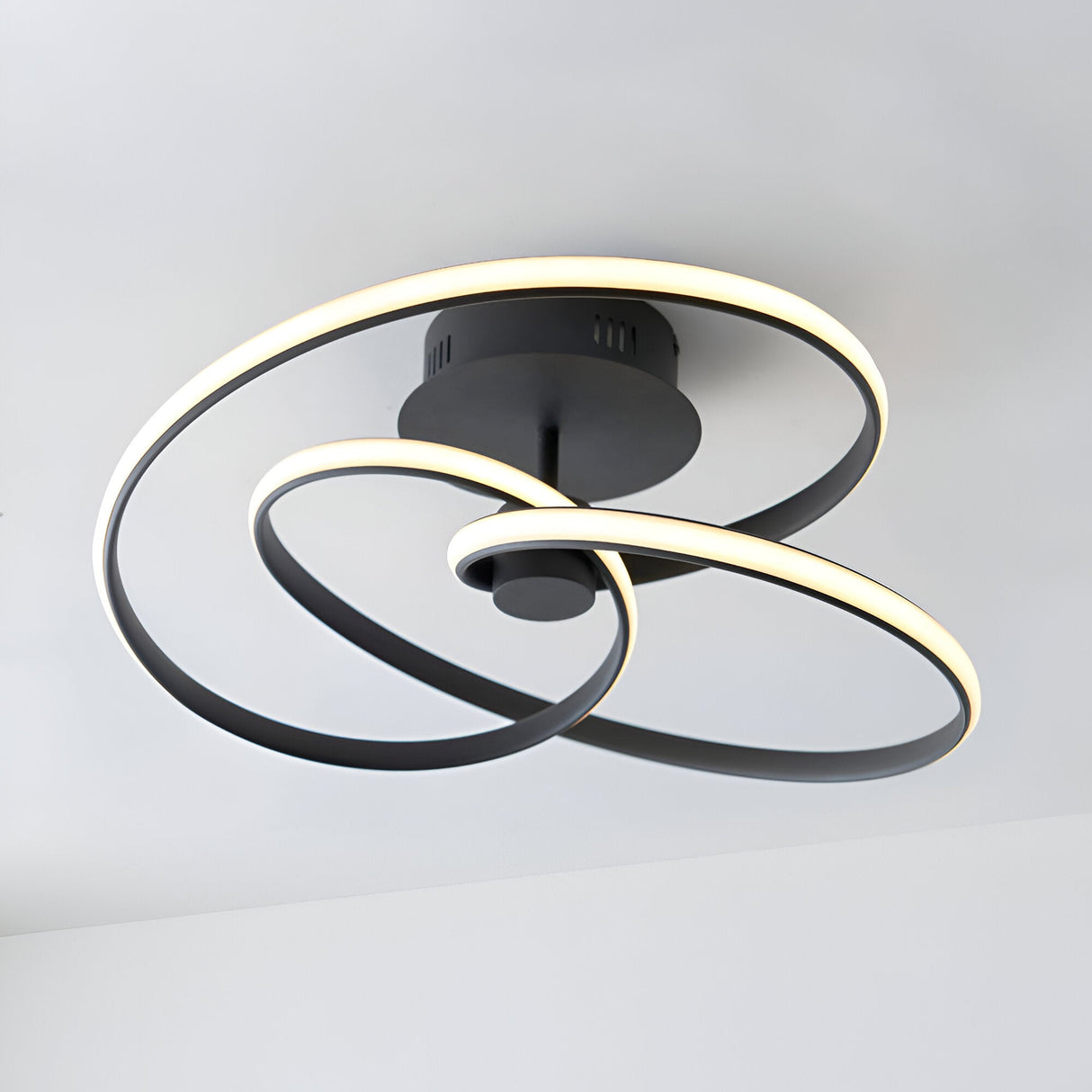 Endon Halden LED semi-flush ceiling light in matt black, with looped intertwined metal bands forming a modern sculptural design on a white ceiling.