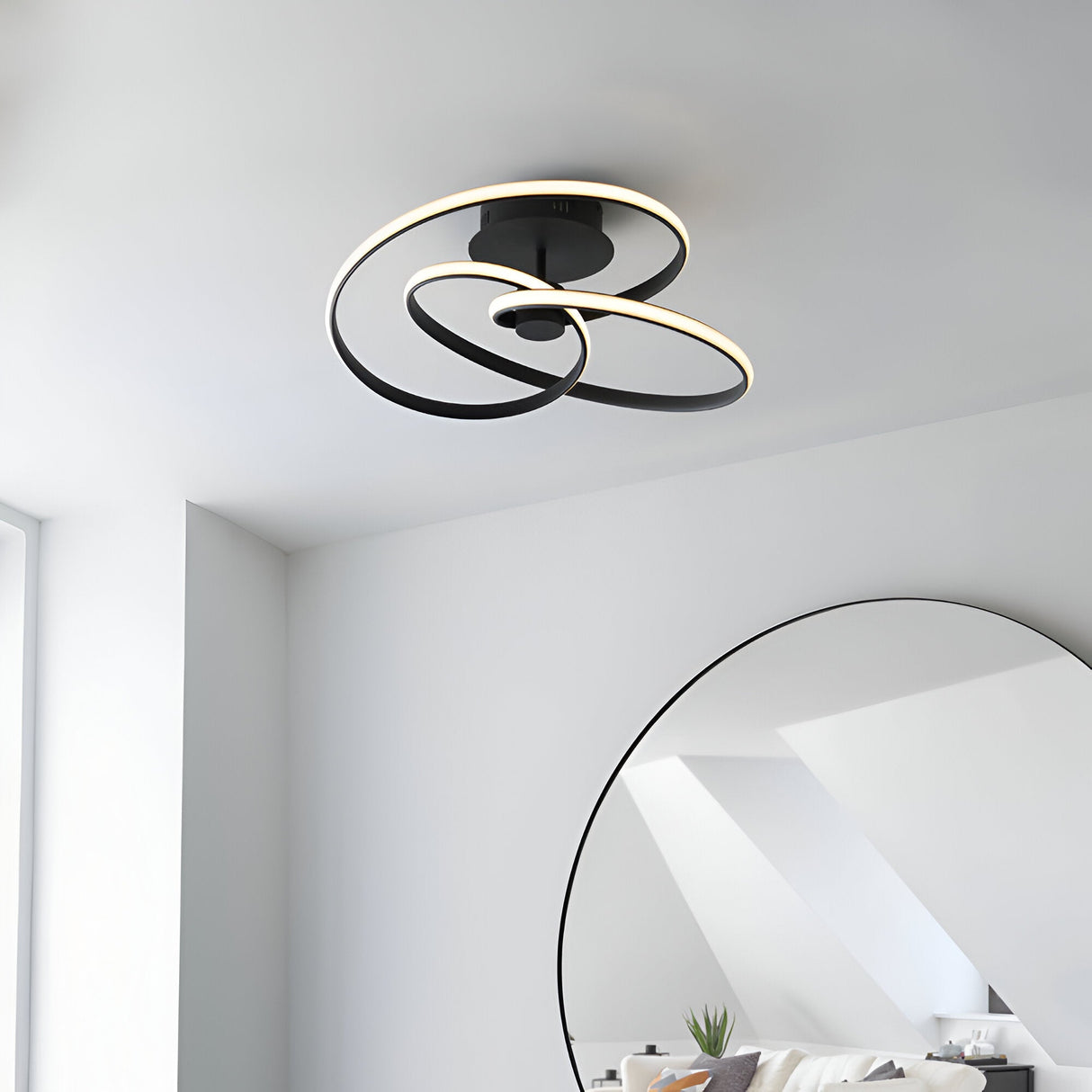 Endon Halden LED semi-flush ceiling light in matt black, featuring looped intertwined rings, mounted on a white ceiling near a round mirror.