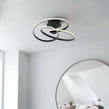 Endon Halden LED semi-flush ceiling light in matt black, featuring looped intertwined rings, mounted on a white ceiling near a round mirror.