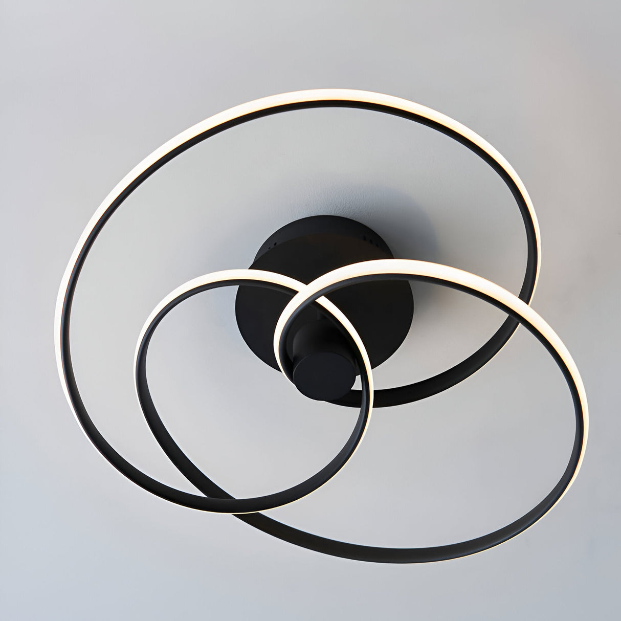 Endon Halden LED semi-flush ceiling light with three interlinked matt black rings around a circular backplate, mounted on a pale ceiling.