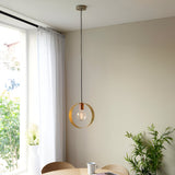 Brenmere Pendant Light with brushed brass hoop frame and exposed bulb, hung from nickel ceiling cap in a dining room setting.