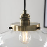 Kedleston Pendant in brass with a clear glass shade, close-up of the knurled E27 lamp holder and exposed bulb against a plain background.