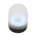 Round LCD flip alarm clock with frosted clear plastic shade glowing white and a black plastic base, upright on a plain white background.
