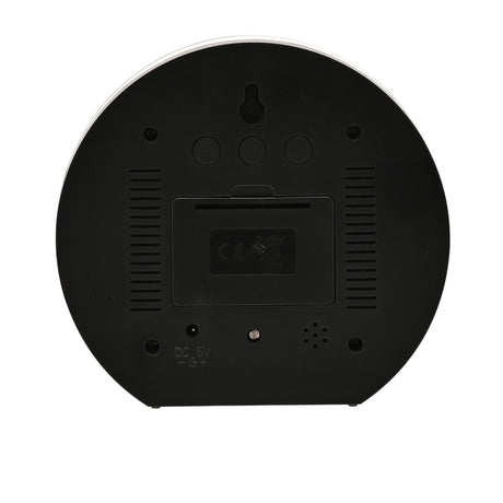 Rear view of the round LCD Flip Mirrored alarm clock in black plastic, showing vent slits, three control buttons, battery compartment, speaker, and DC 5V port on a plain white background.