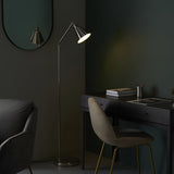Endon Brackley nickel floor lamp with adjustable arm and cone shade, lit beside a dark desk and chair in a green-walled room with oval mirror.