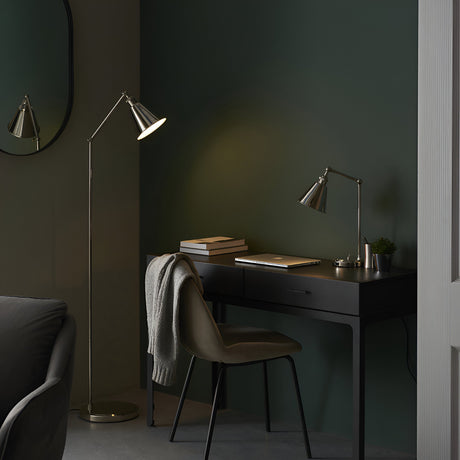 Endon Brackley nickel floor lamp with adjustable arm and conical shade beside a black desk and chair in a dark green bedroom workspace.