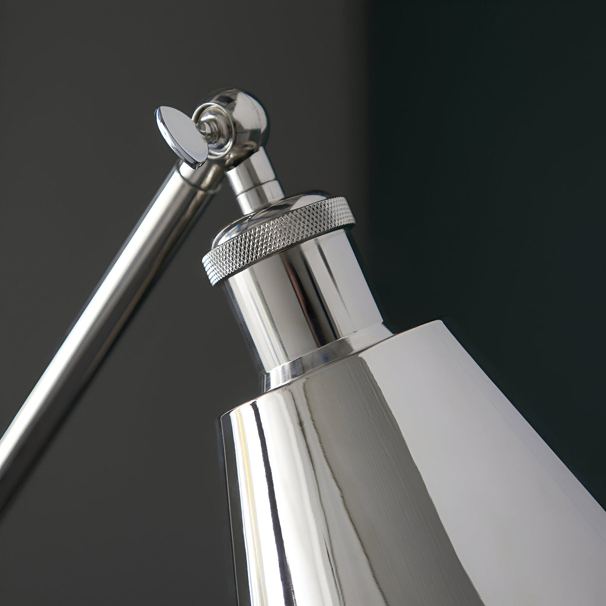 Close-up of the Endon Brackley floor lamp head and adjustable arm joint in bright nickel plate with knurled detailing against a dark background.