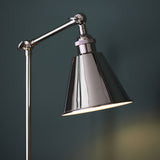 Endon Brackley table lamp in bright nickel with knurled detailing, adjustable arm and conical shade, lit against a dark teal background.