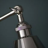 Close-up of Endon Brackley table lamp head in bright nickel, showing knurled ring detail, adjustable joint and toggle switch against a dark teal backdrop.