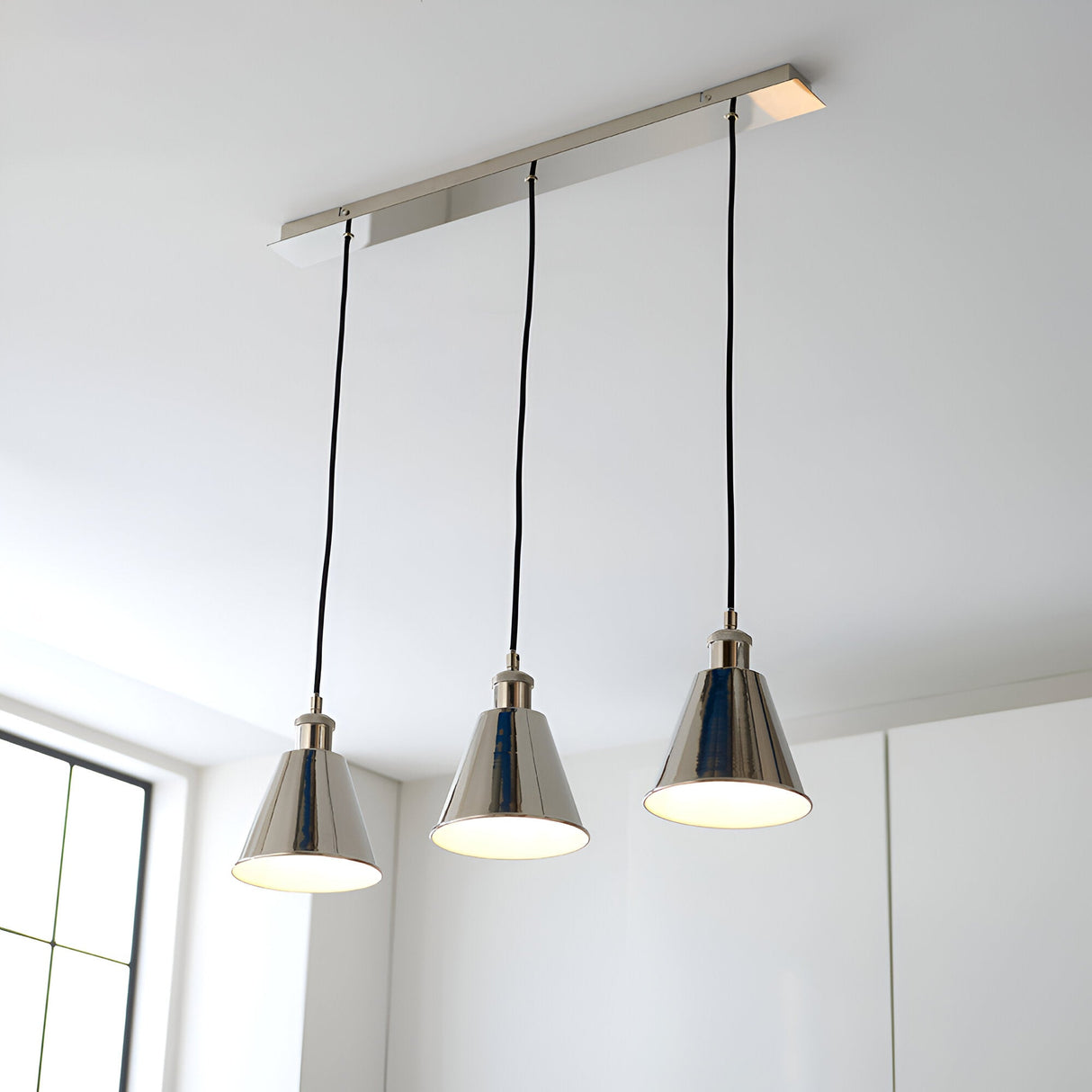 Endon Brackley 3 Light Linear Pendant in nickel with satin white inner shades, cone-shaped lamps on black flex, installed above a bright kitchen.