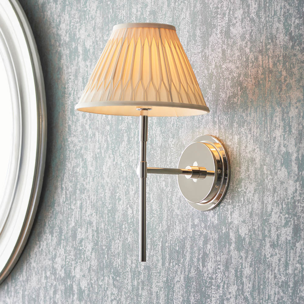 Endon Chartwell wall light in nickel with slim upright bracket and pleated cream fabric shade, mounted beside a round mirror on textured grey wall.