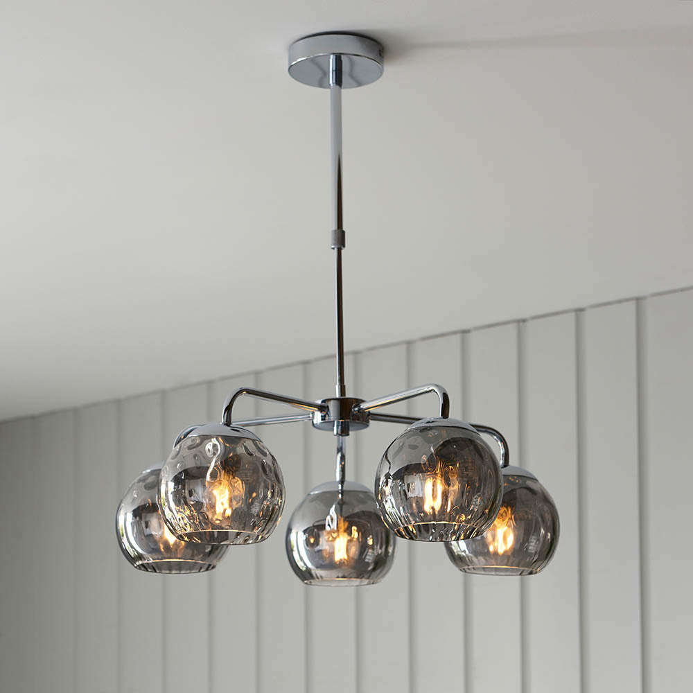 Draycott 5 Light Dimpled Glass Pendant in chrome, with five smokey mirrored globe shades on a chrome frame, shown hanging from a panelled ceiling.