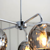 Close-up of the Draycott 5 Light Dimpled Glass Pendant in chrome, showing the central ceiling plate with radiating metal arms and smokey mirrored glass shades.