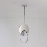 The Half Moon LED Pendant Light - Silver features a circular silver fixture partially covering a flat white diffuser, suspended by a black cord against a plain white ceiling and wall.