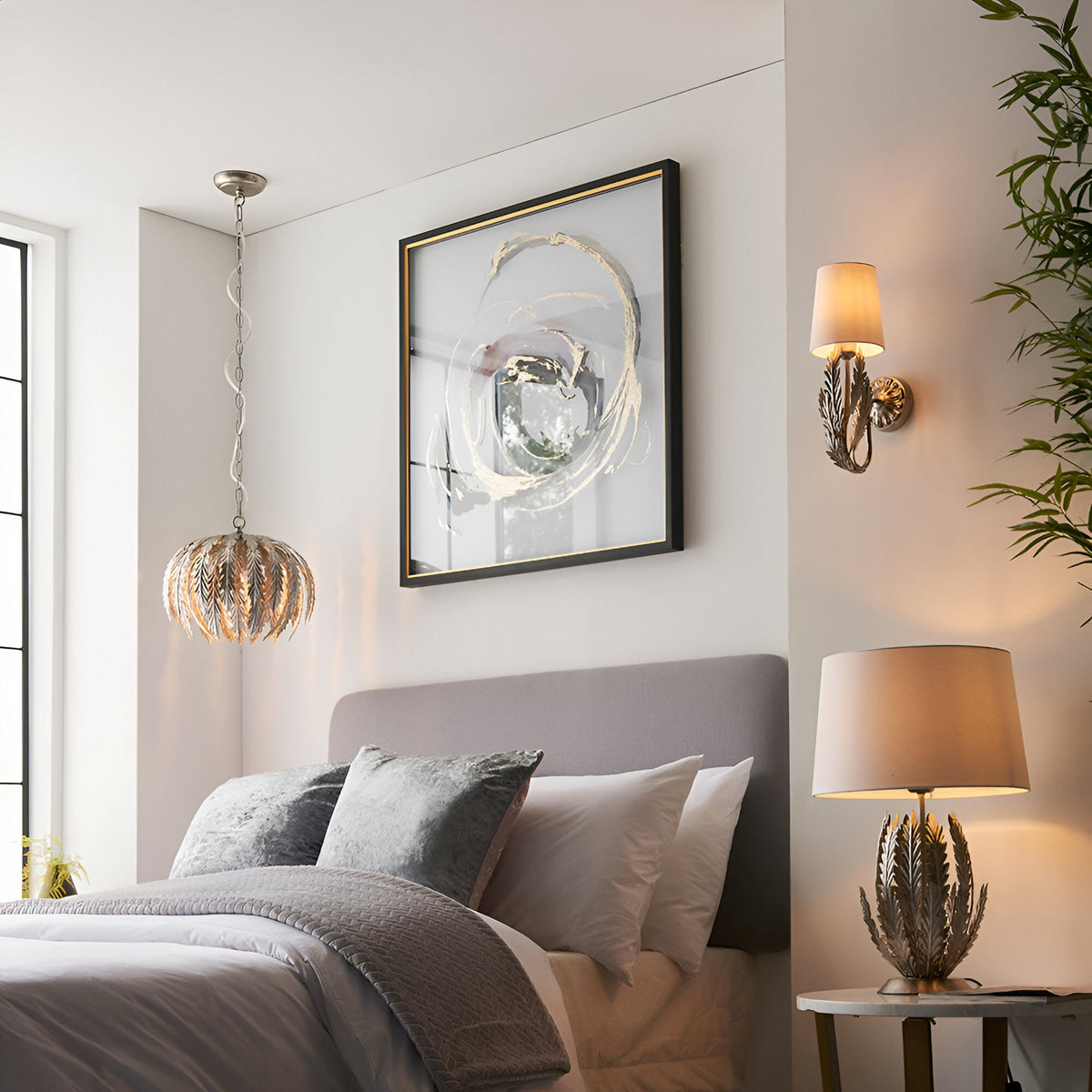 Endon Colette table lamp with layered silver leaf metal base and ivory cotton shade on a bedside table, beside a matching pendant in a grey bedroom.