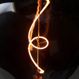4W E27 LED Filament Wisp Bulb in smoke glass, showing a swirling wisp-shaped filament glowing warm white against a dark background.
