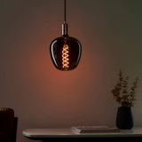 Endon 4W E27 LED filament helix bulb in smoked glass with warm white spiral filament, shown lit in a copper pendant holder above a marble console table.