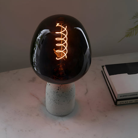 Endon 4W E27 LED filament helix bulb with smoked glass and warm white spiral filament, set in a terrazzo holder on a marble surface beside books.