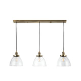 Wentworth 3 Light Linear Pendant in antique brass, with clear glass dome shades on black flex cords along a linear bar, shown on a white background.