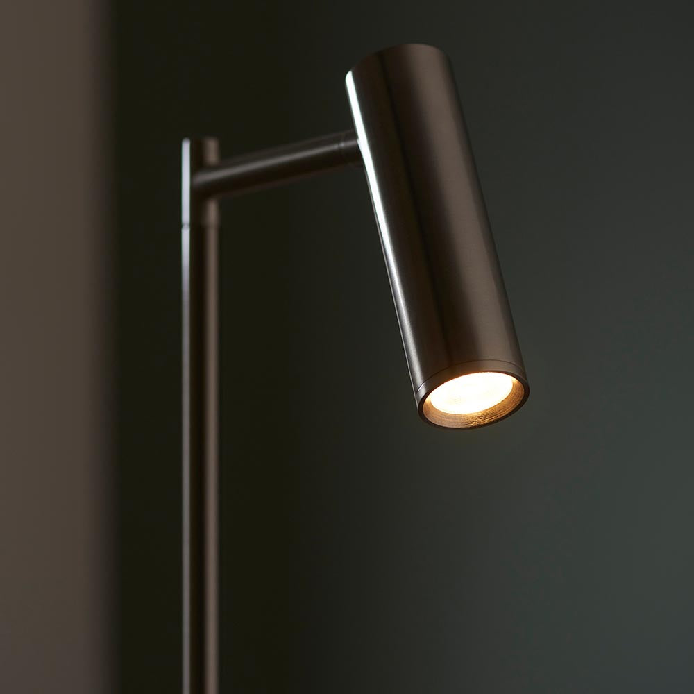 Endon Brackbourne floor lamp with an adjustable cylindrical satin nickel head illuminated warm white, shown against a dark background.