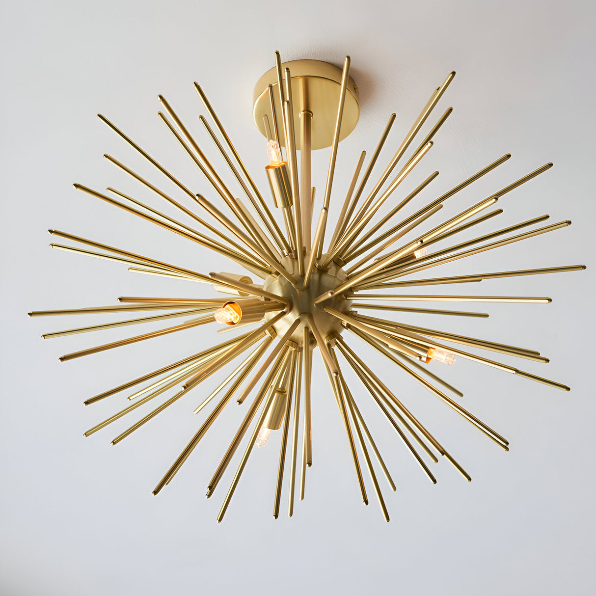 Endon Merrick 6 Light semi-flush ceiling light with radiating brass spike arms in a warm brass finish, mounted to a white ceiling.
