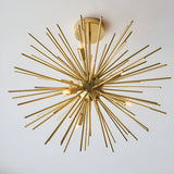 Endon Merrick 6 Light semi-flush ceiling light with radiating brass spike arms in a warm brass finish, mounted to a white ceiling.