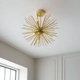 Endon Merrick 6 light semi-flush ceiling light with brass sunburst spike design, mounted on a white ceiling in a neutral room with panelled walls.