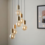 Marlowe 6 Light Pendant in soft gold, staggered globe bulbs on grey fabric flex, hanging in a room beside a framed wall print.