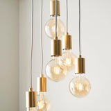 Marlowe 6 Light Pendant in gold, cluster of globe bulbs on staggered grey fabric flexes, shown against a plain light wall.