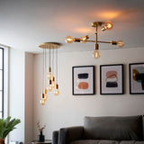 Marlowe 6-Light Pendant in gold with exposed bulbs on staggered cords, shown in a living room near a brass sputnik ceiling light and framed wall art.