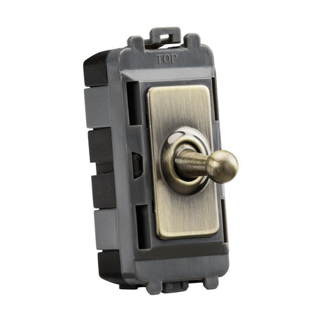 The 20AX 1 Gang 2-Way SP Grid Toggle Switch features a rectangular metallic body and lever mounted on a square base labeled TOP. It has an antique brass finish, crafted from premium-grade steel, and is designed for electrical control in household installations compatible with the Knightsbridge Grid system.