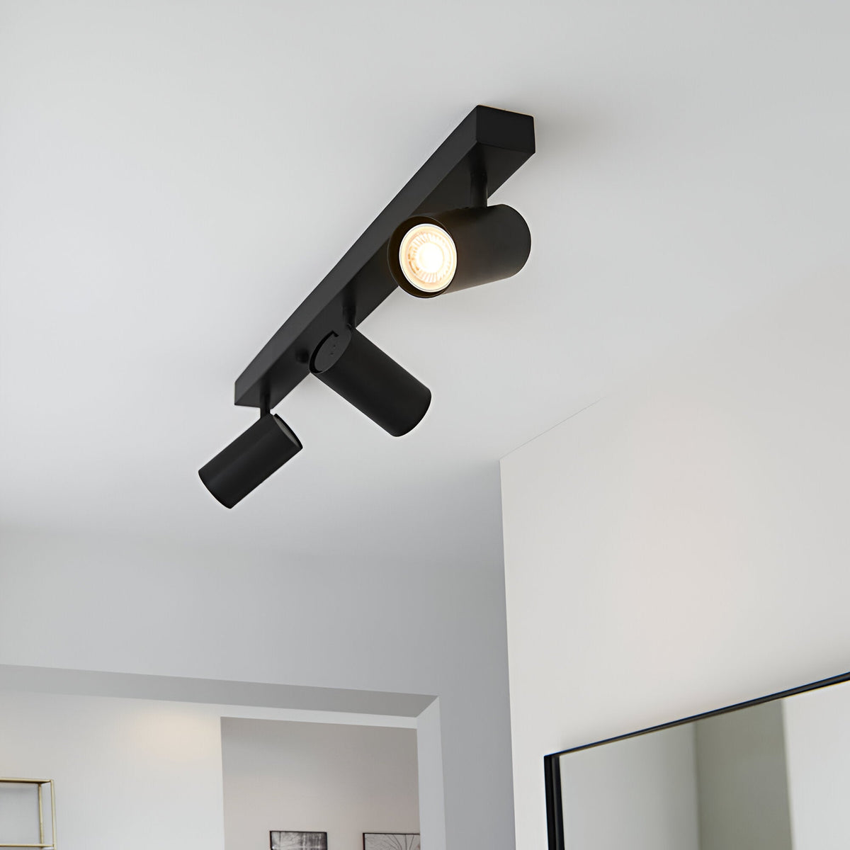 Calder 3 Light Spotlight Plate in matt black metal, angled ceiling fitting with GU10 heads, shown lit on a white ceiling.