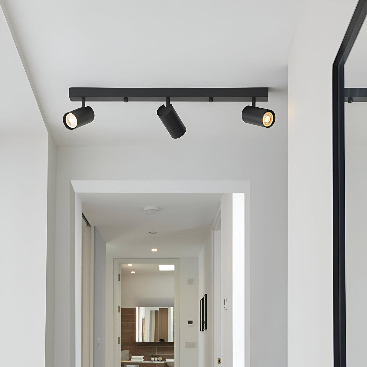 Calder 3 Light Spotlight Plate in matt black metal, three angled GU10 heads on a bar, fitted to a hallway ceiling.