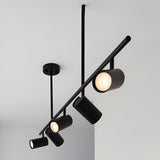 Calder 5 Light Spotlight Bar in matt black metal with adjustable cylindrical heads on a slim diagonal bar, ceiling-mounted against a light grey ceiling.