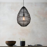 Endon Chartdale teardrop pendant light in hand-woven black rattan with an E27 bulb, hung above a dining setting with dark bowls and a potted plant.