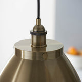 Close-up of Endon Bramdale Medium Pendant in antique brass, showing the rolled-edge metal shade top, knurled lamp holder and black fabric flex.