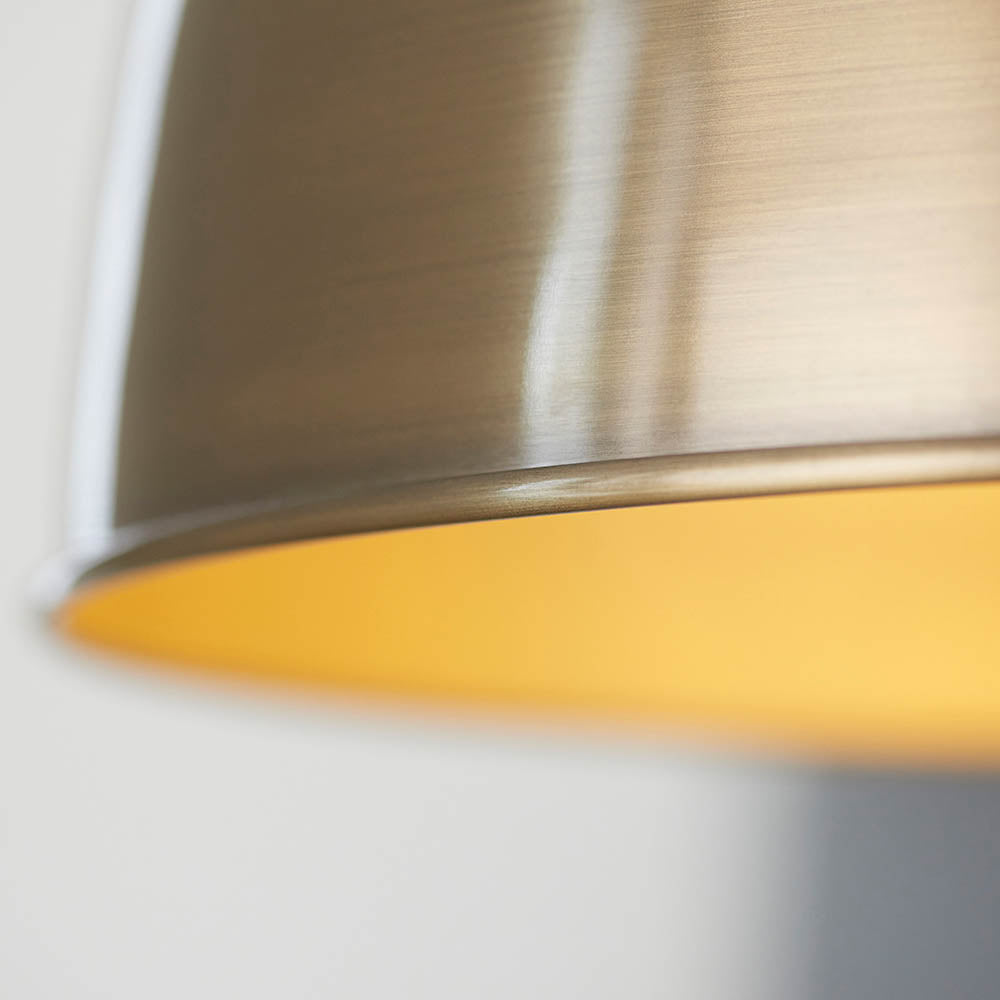 Close-up of Endon Bramdale medium pendant shade rim in antique brass, showing the rolled edge and warm yellow interior.