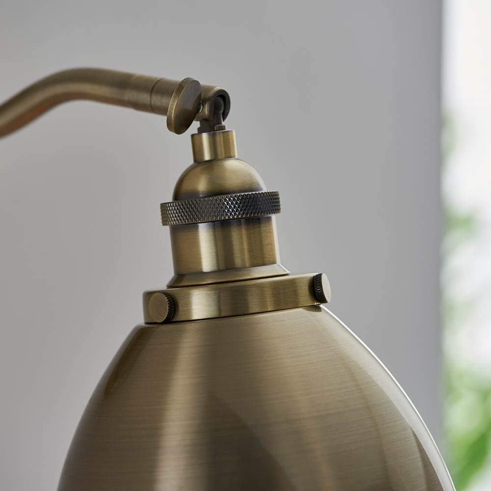 Close-up of Endon Bramdale wall light in brass, showing the adjustable knuckle joint, knurled lamp holder, and domed metal shade.
