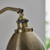 Close-up of Endon Bramdale wall light in brass, showing the adjustable knuckle joint, knurled lamp holder, and domed metal shade.